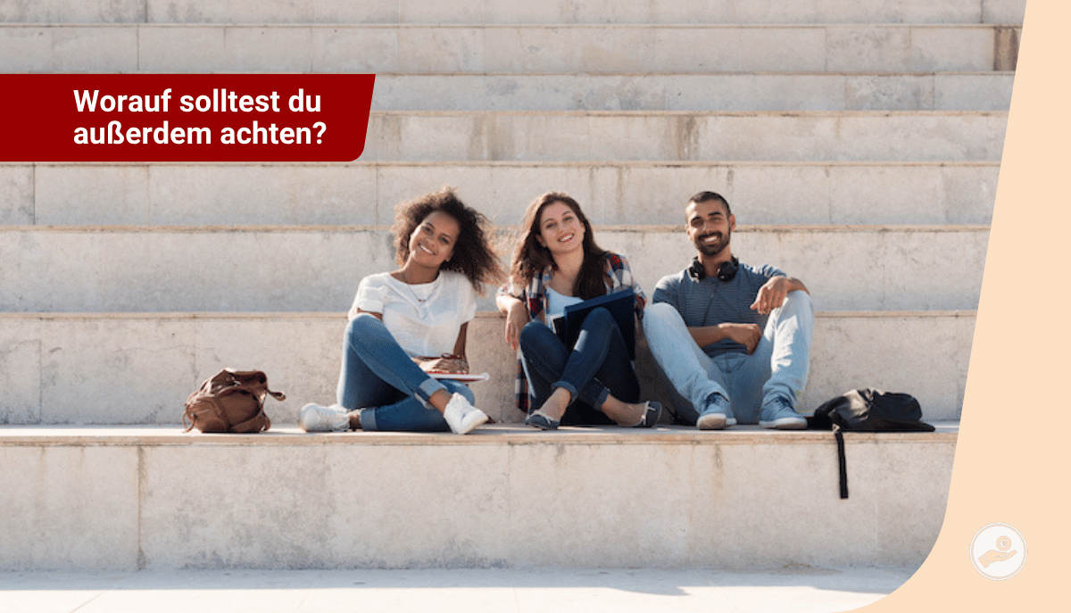 Drei junge Lehramtsstudierende sitzen entspannt auf einer steinernen Treppe, lächeln in die Kamera, Taschen und Lernmaterialien neben ihnen.